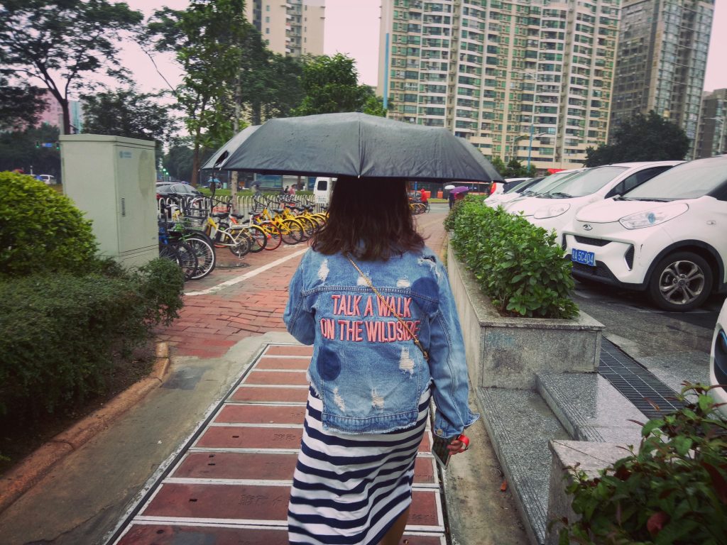 chinese woman with a denim jacket that has misspelled english words