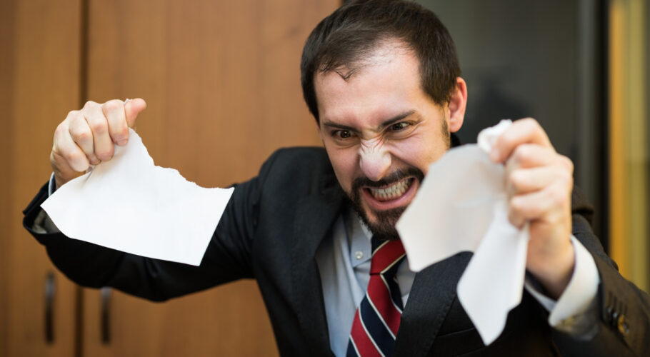 angry businessman tearing apart document in teaching english office in china