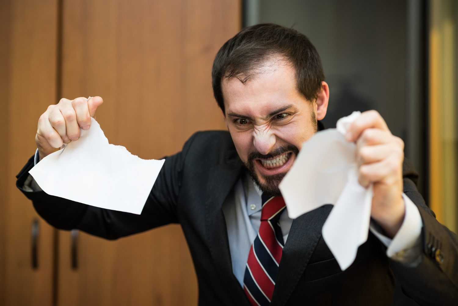 angry businessman tearing apart document in teaching english office in china