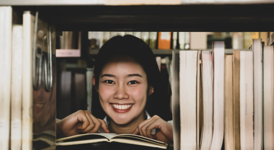asian female college student research learn from textbooks shelf school library