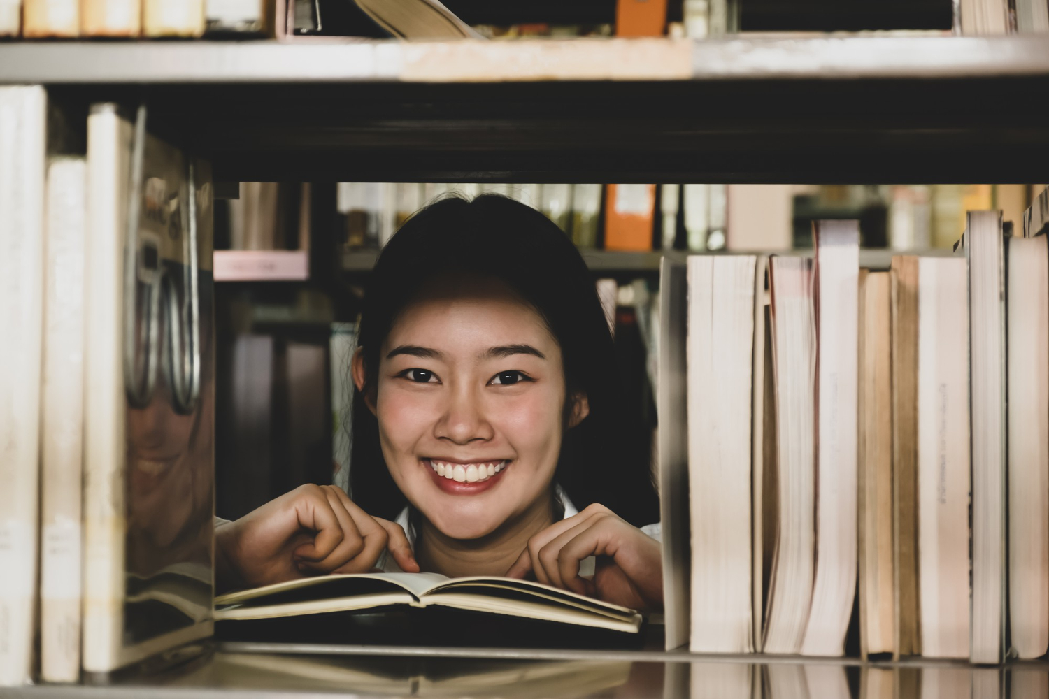 asian female college student research learn from textbooks shelf school library