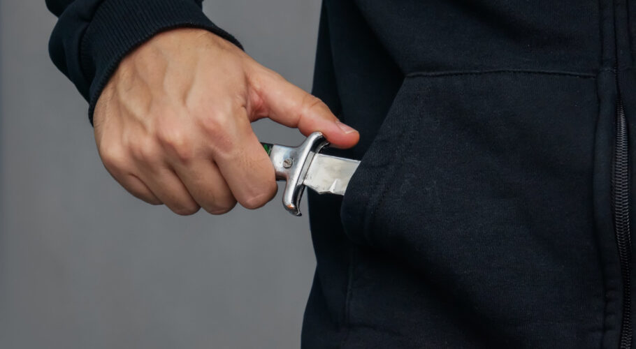 young male pulls a folding knife out of his pocket in a threatening manner