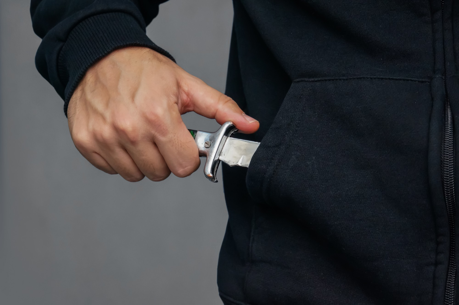 young male pulls a folding knife out of his pocket in a threatening manner