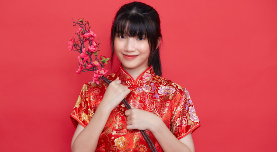 beautiful asian woman in red traditional chinese dress holding sakura branch