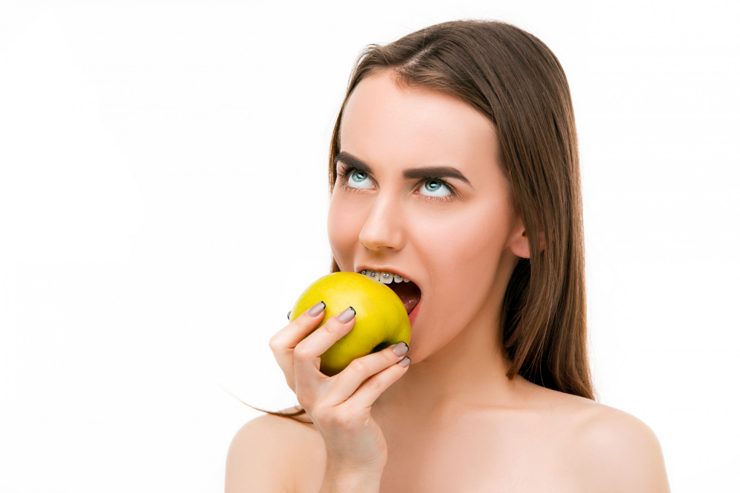 beautiful young woman tabitha with braces on teeth biting apple