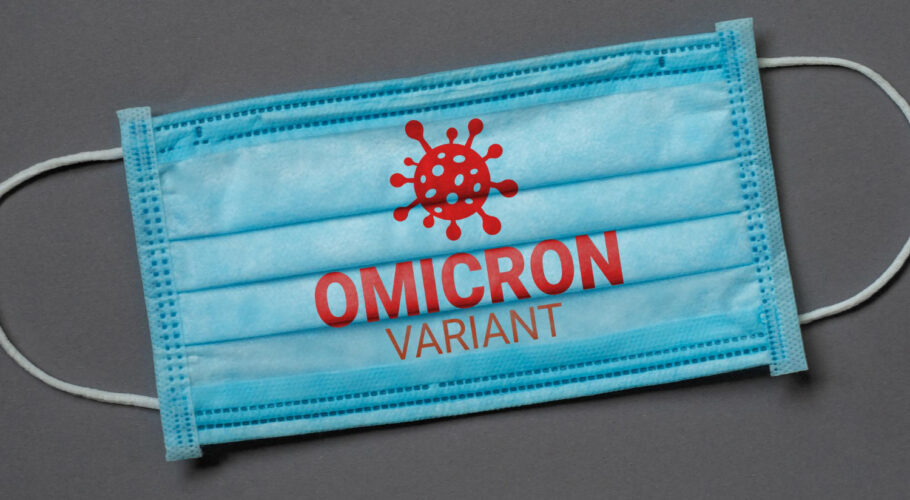 blue medical face mask lies dark grey background with inscription omicron variant coronavirus