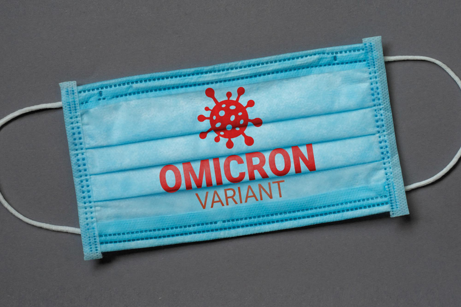 blue medical face mask lies dark grey background with inscription omicron variant coronavirus