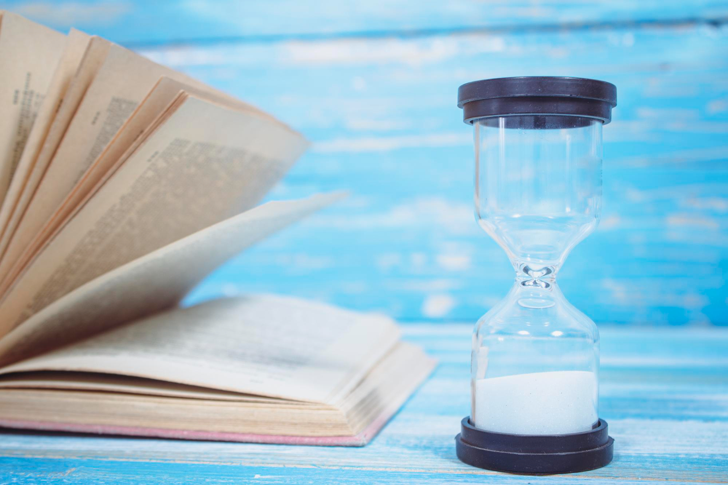 books hourglass blue wooden table time reflecting