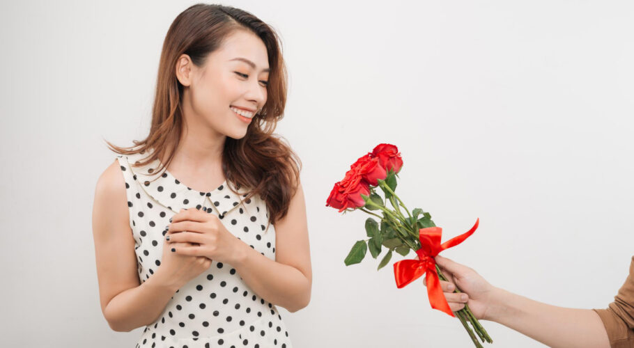 cheerful charming young woman receiving bunch flowers from her boyfriend