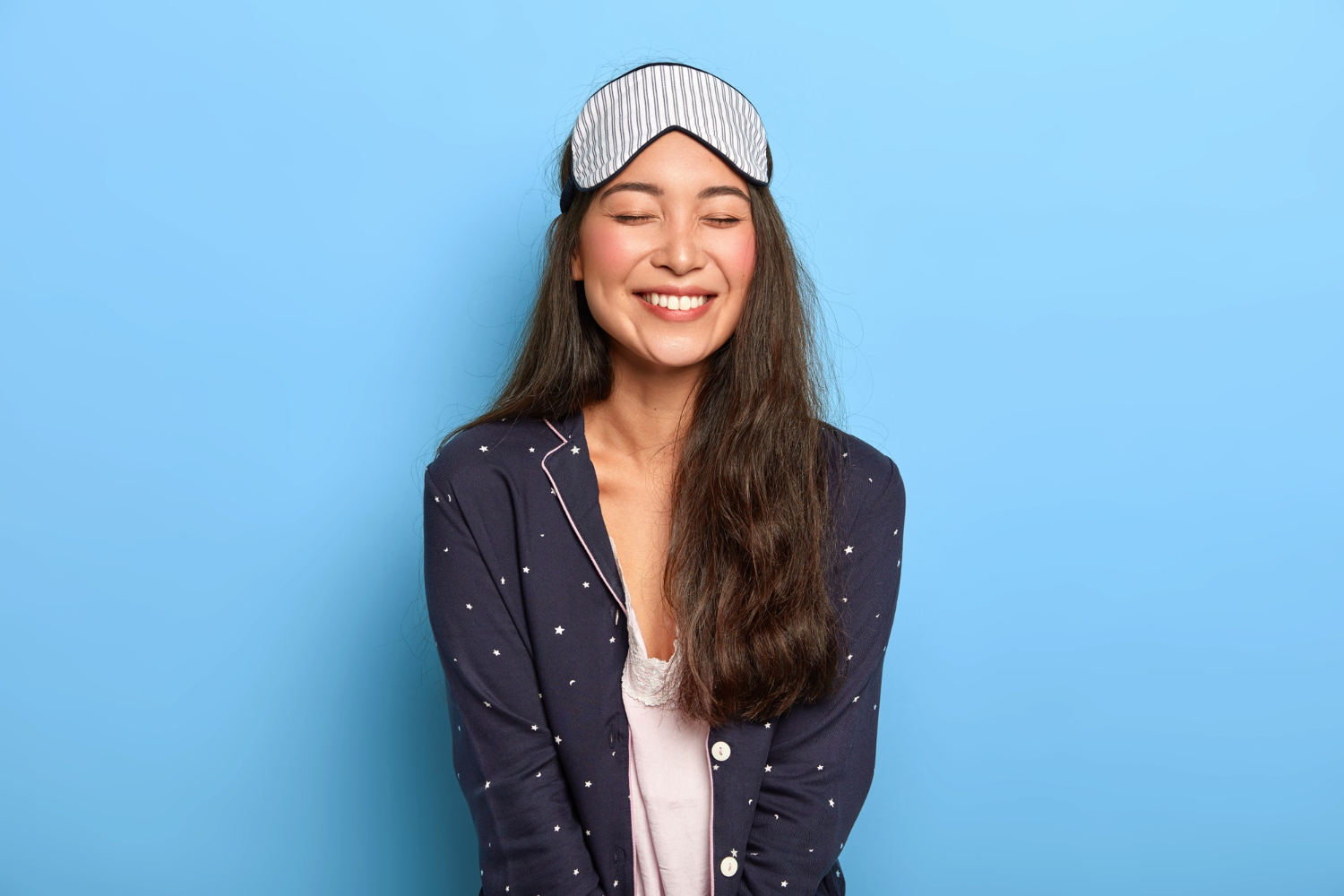 cheerful woman with pleasant toothy smile wears comfortable pyjamas sleep mask enjoys bedtime routine china