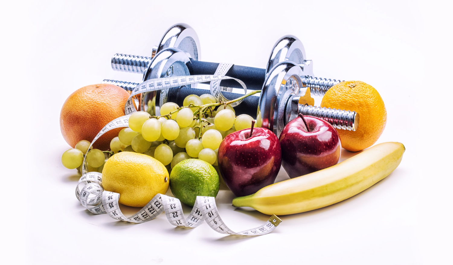 chrome dumbbells surrounded with healthy fruits and measuring tape calorie diet