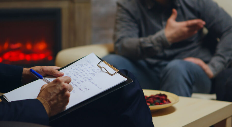 close up psychologist writing notes while couple yelling relationship guidance