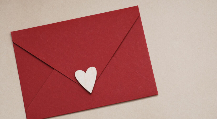 close up red paper envelope with white heart neutral brown background love