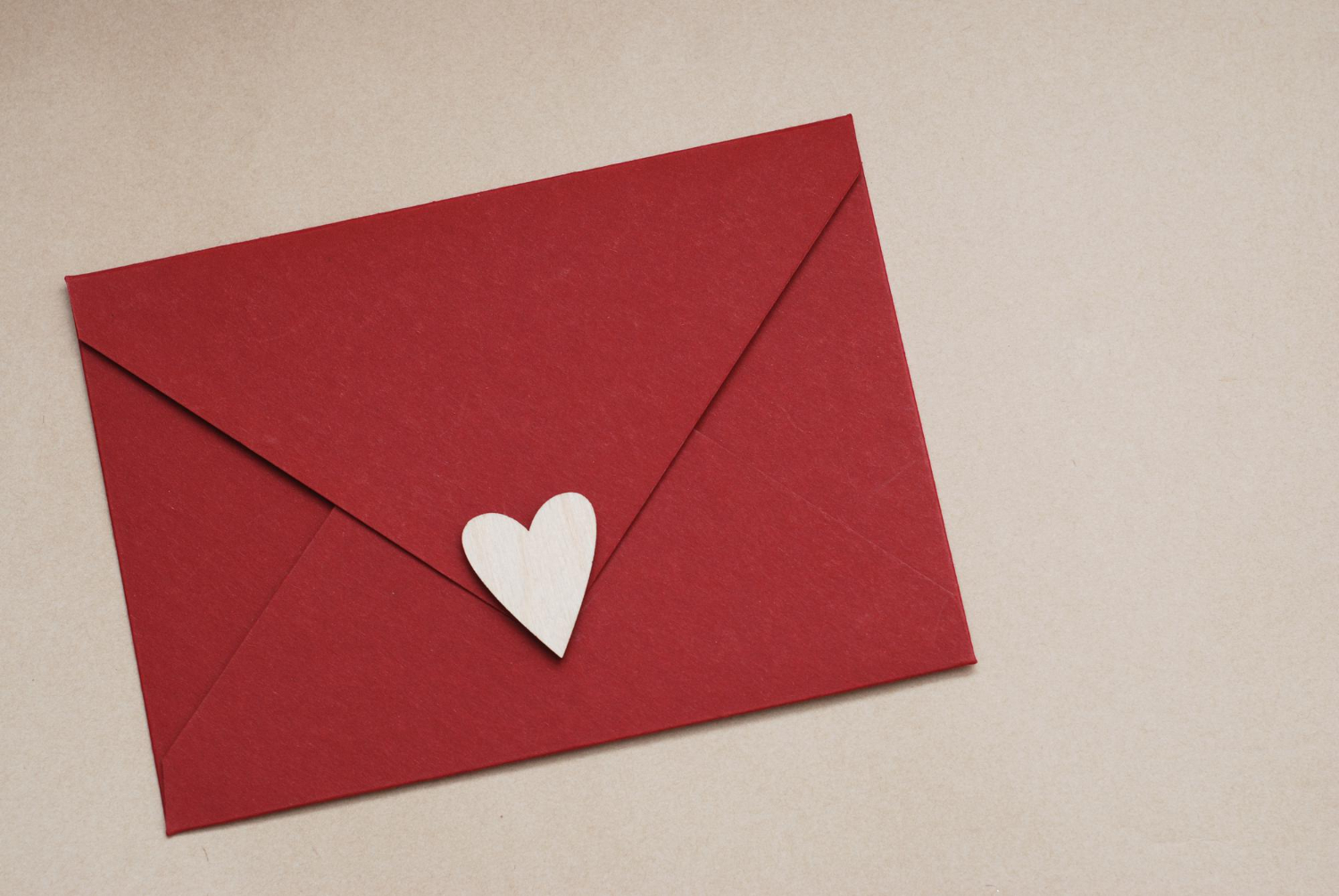 close up red paper envelope with white heart neutral brown background love