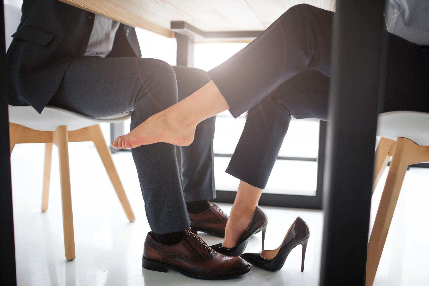 young man and woman playing footsies under a table seated together