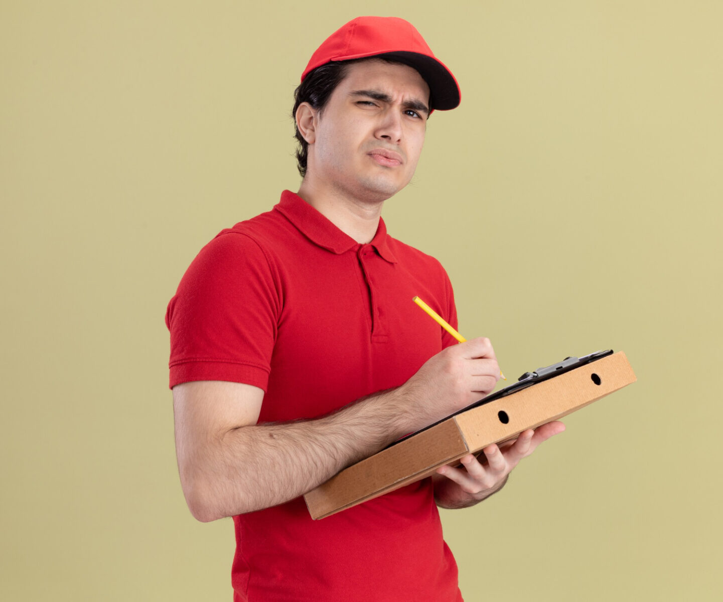 confused young caucasian pizza hut delivery man in red uniform holding pizza and clipboard