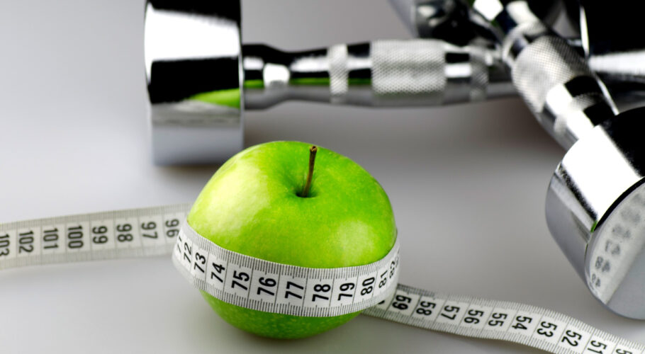 dumbbells with measuring tape apple diet concept background