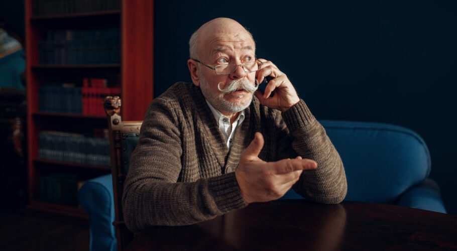 elderly man talking by mobile phone home office