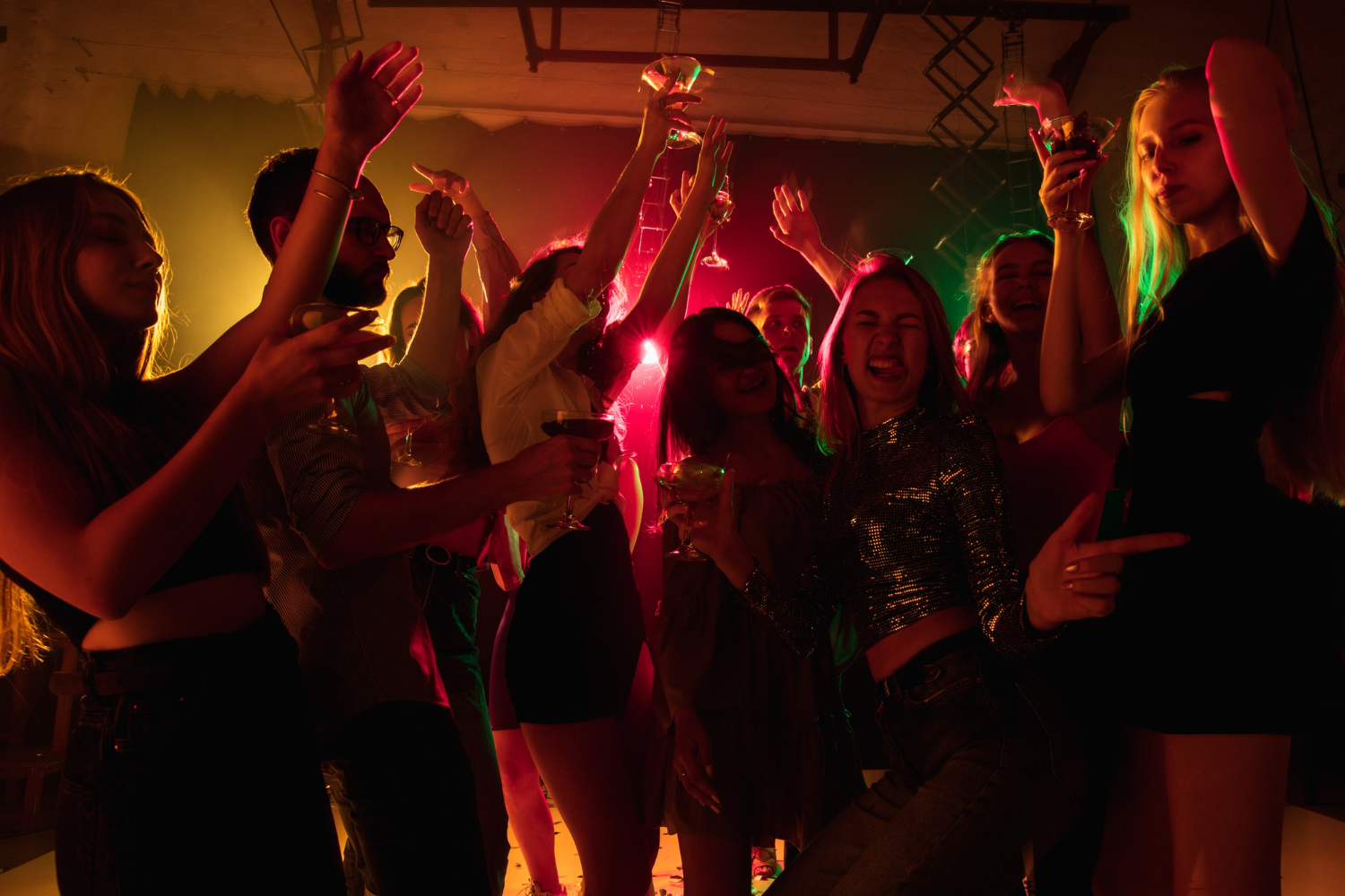emotions crowd of people raising their hands dancing on dancefloor with neon light night life