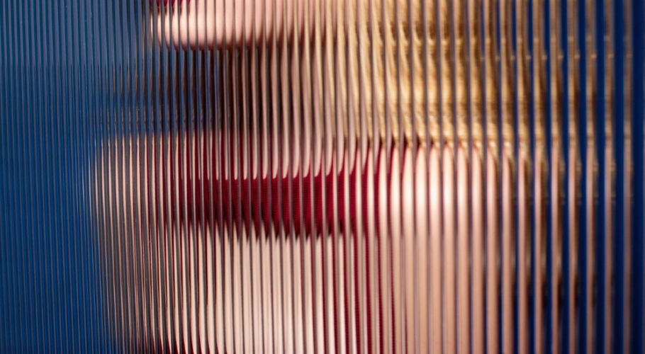 blonde fashion model jewell with red dress and lipstick behind striped corrugated glass
