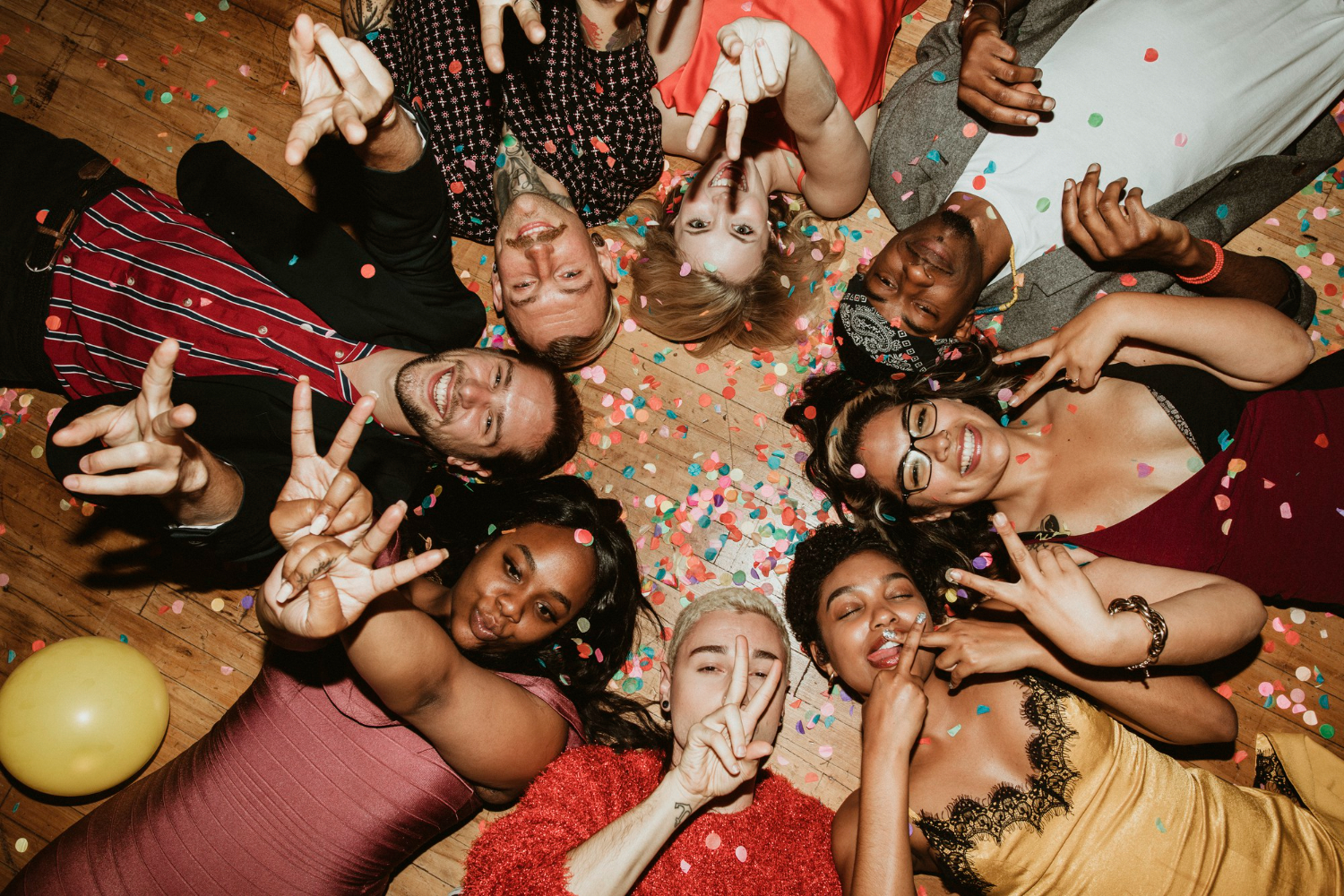 friends lying on the floor at a house party with balloons and drinks