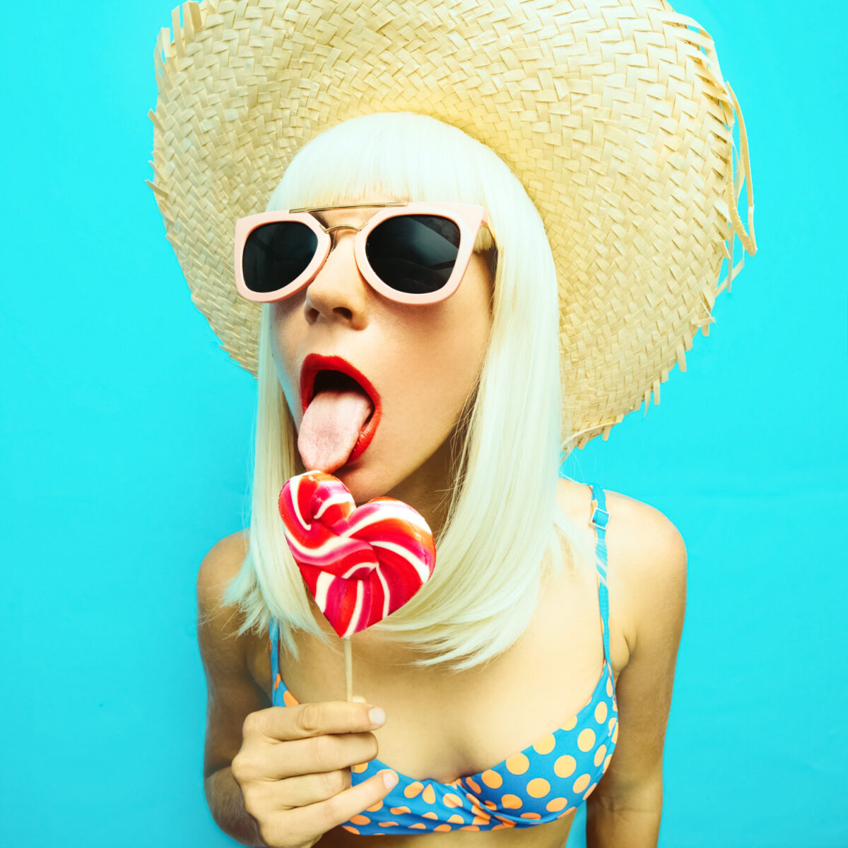 sensual blonde in polka dot blue swimsuit licking lollipop retro style