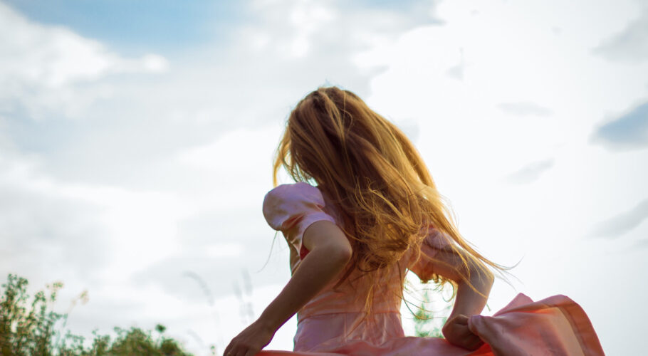 girl running across field pink dress