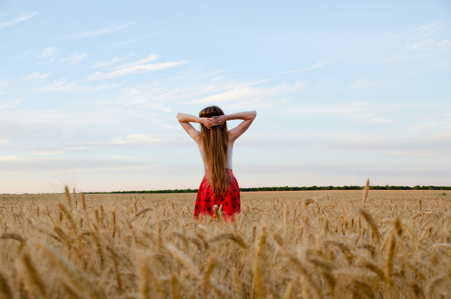 girl standing wheat field with his hands his head night sky seen from