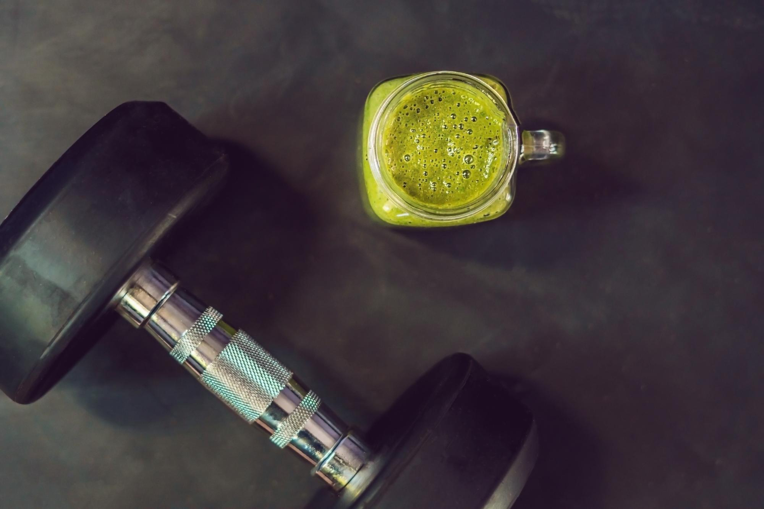 green smoothie with dumbbells at the gym