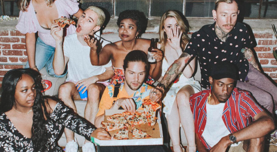 group of diverse friends enjoying pizza at house party