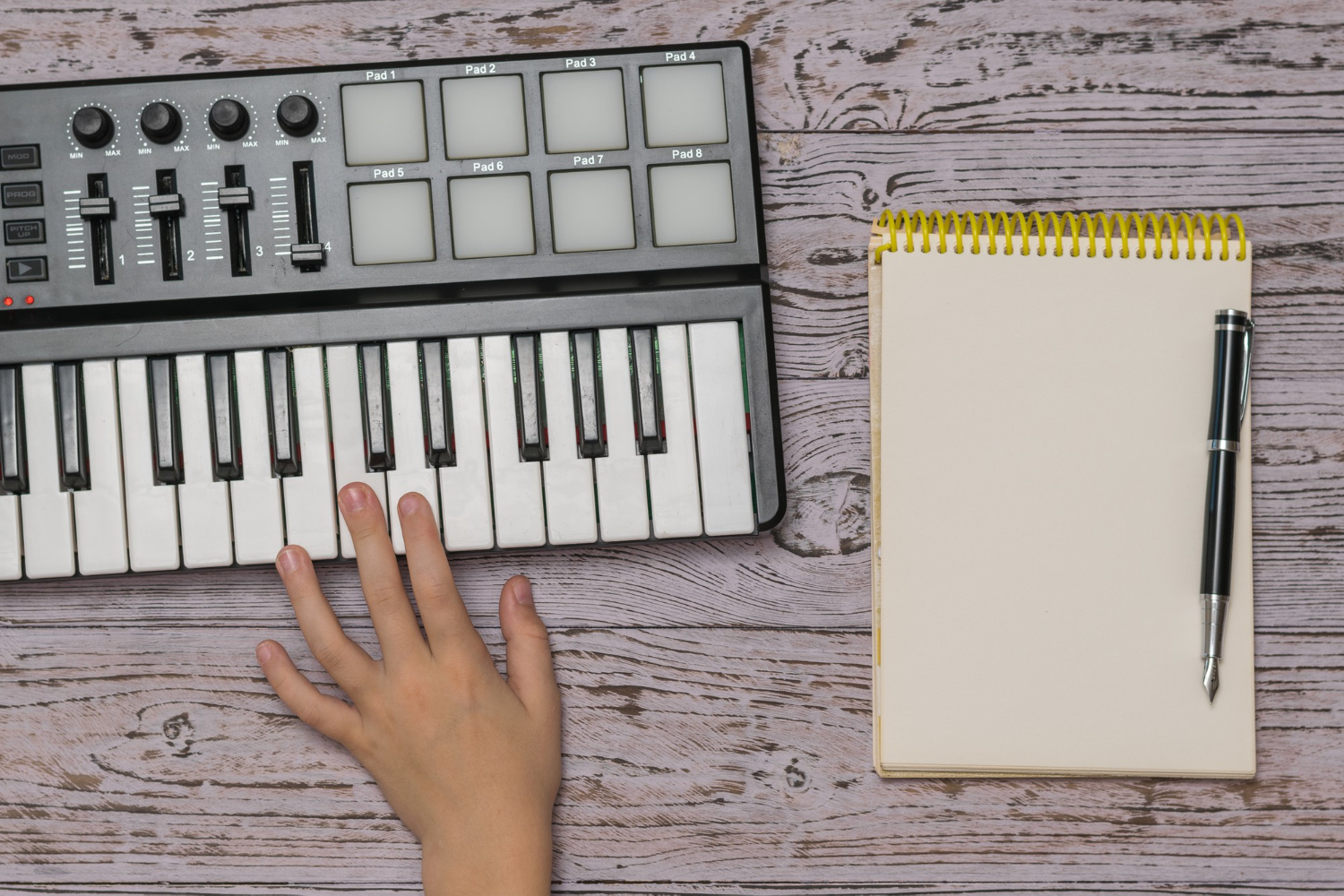 hand music mixer notebook with pen wooden table