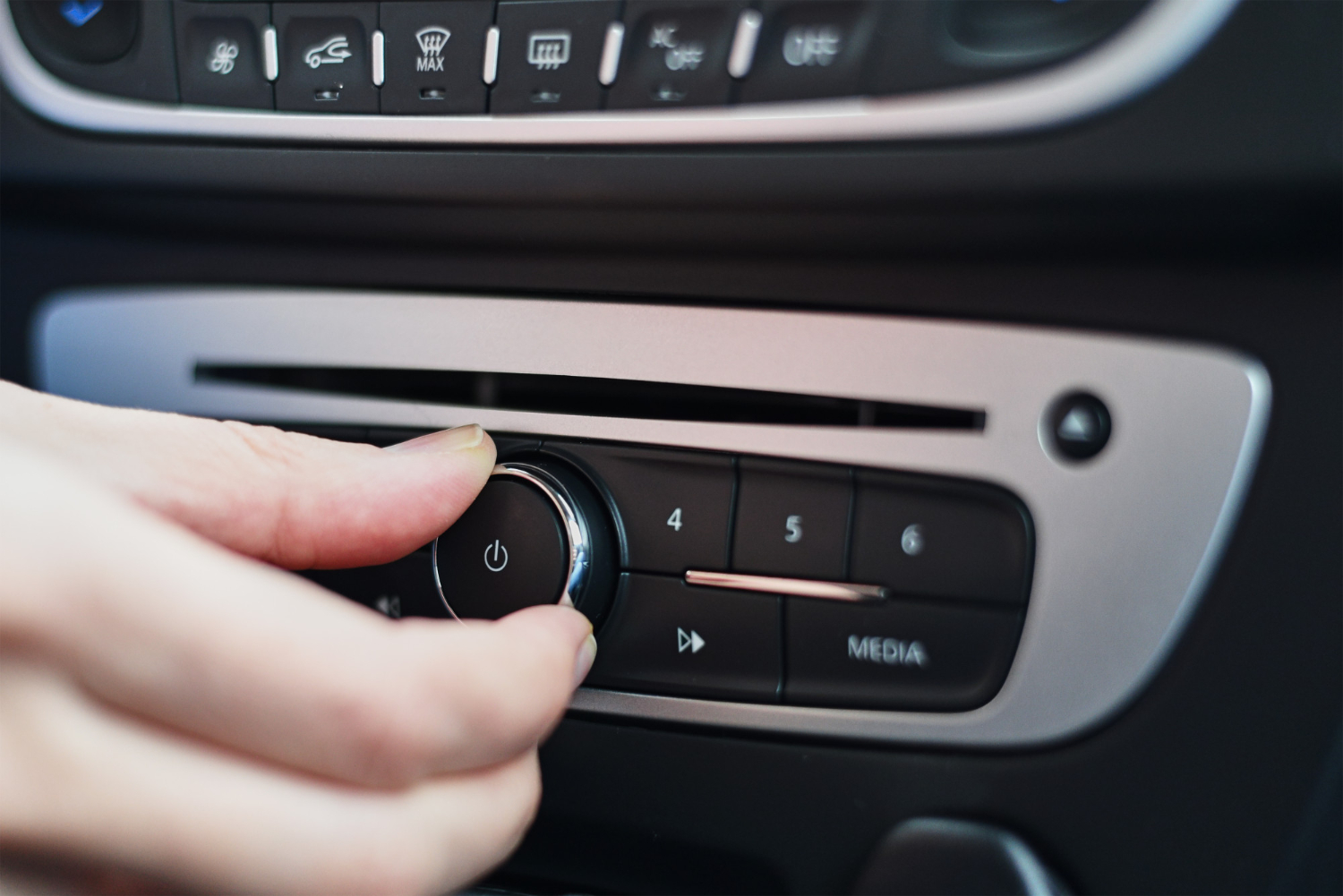 hand pressing a button on a car radio