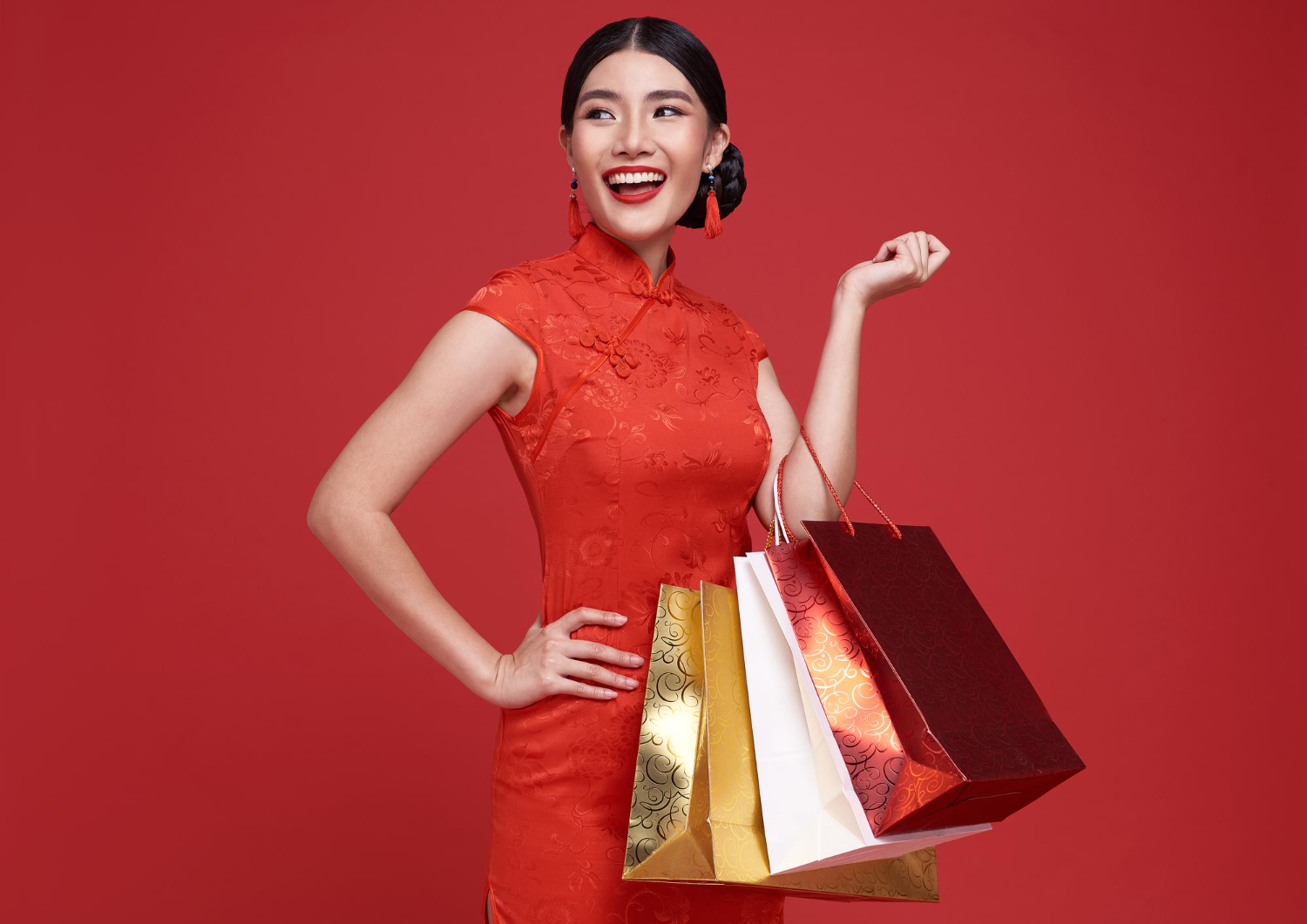 happy asian shopaholic woman wearing traditional cheongsam qipao dress holding shopping bag
