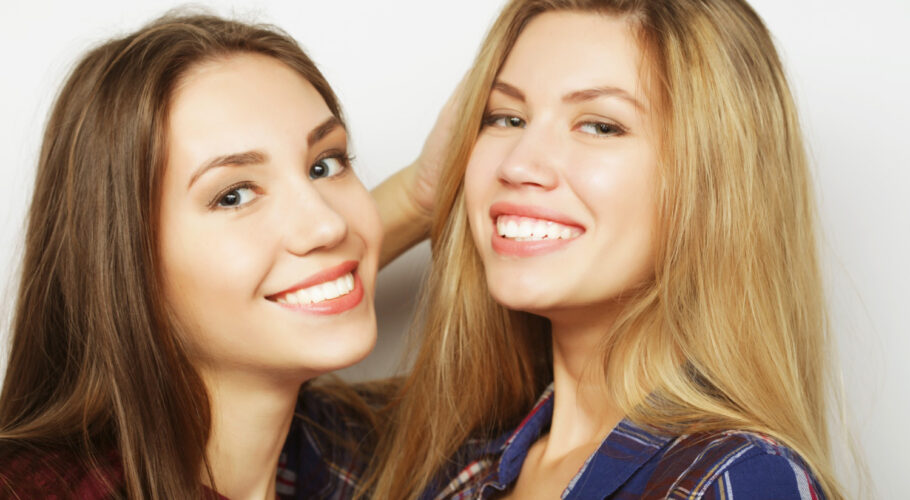 two young girl friends smiling together having fun at party