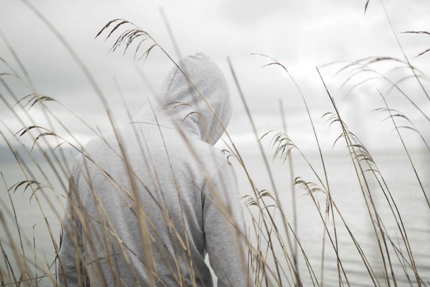 lonely sad male with white hoodie sitting near the sea thinking about life