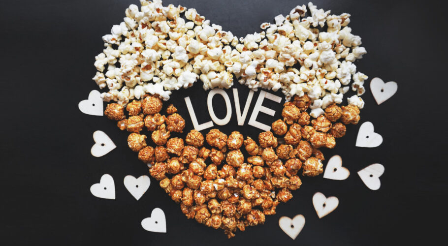 love cinema with popcorn arranged in a heart shape and assorted popcorn set on a background of sweet and salty popcorn