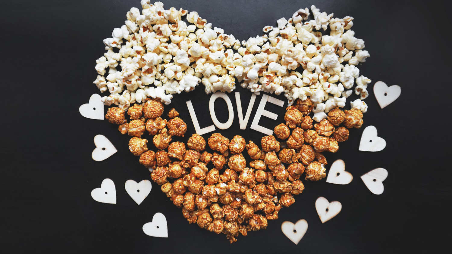 love cinema with popcorn arranged in a heart shape and assorted popcorn set on a background of sweet and salty popcorn