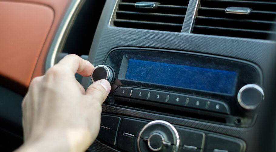 man hand adjusting a dial button on car audio control retro