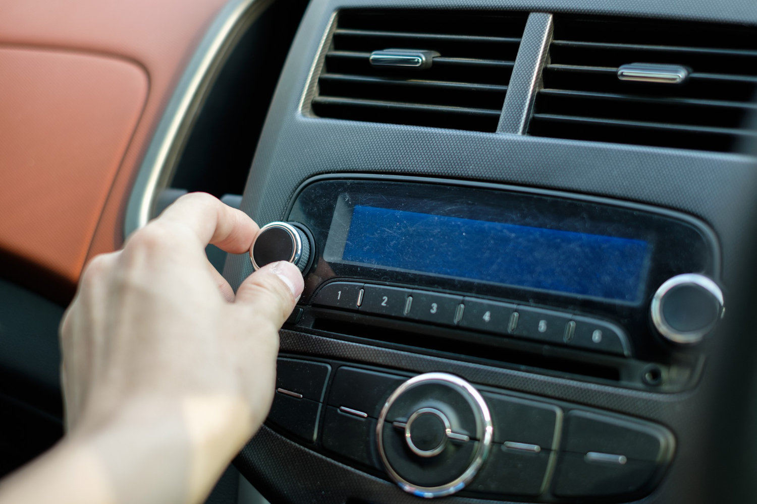 man hand adjusting a dial button on car audio control retro