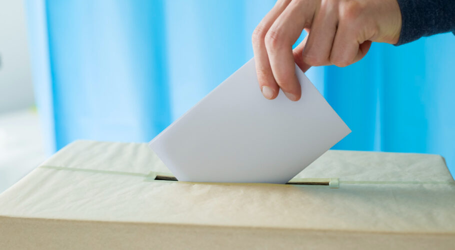 hand throws ballot paper voting polling station during elections