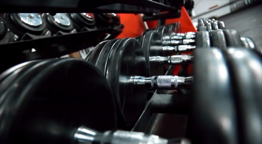 many black dumbbells on a rack for bodybuilding in gym