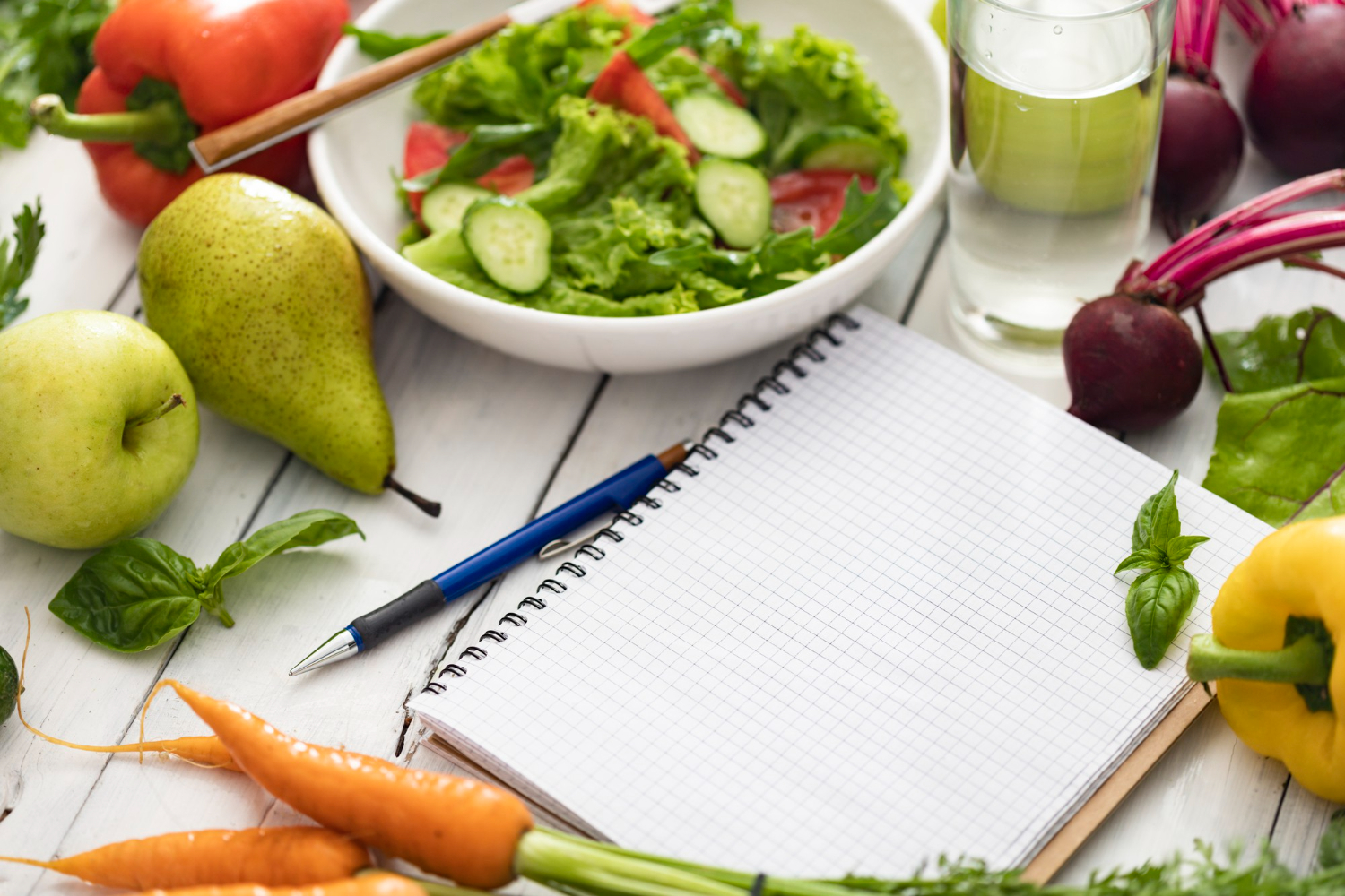 notepad with blank pages and bowl of fresh salad ingredients for a healthy clean food plan and healthy lifestyle