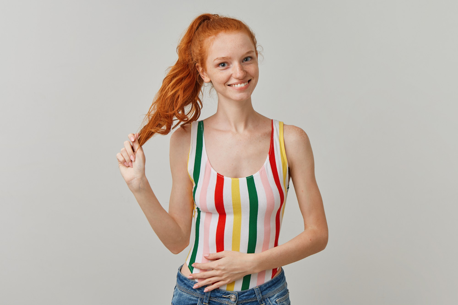 portrait attractive happy girl with ginger pony tail freckles wearing striped colorful swimsuit jeans