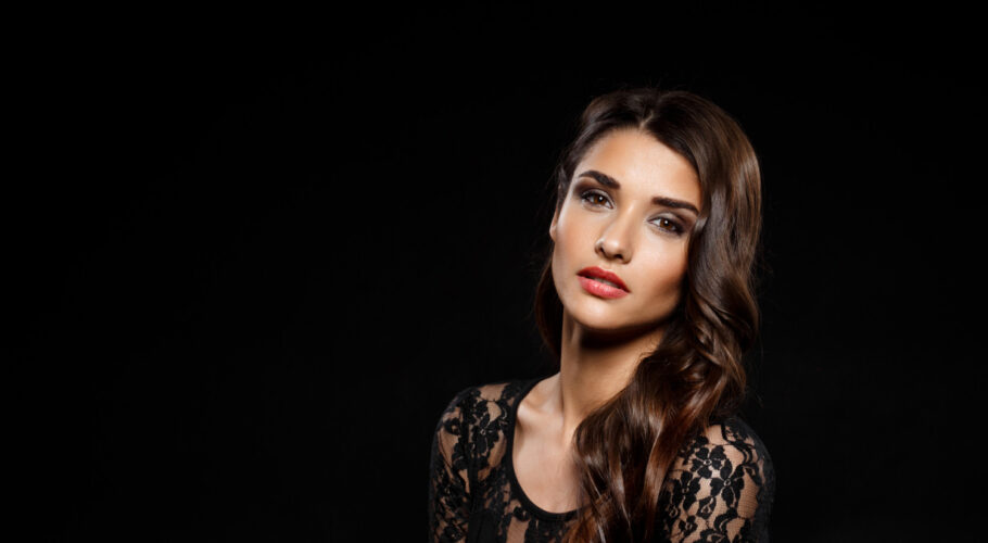 portrait of a beautiful latin woman in a black dress on dark wal