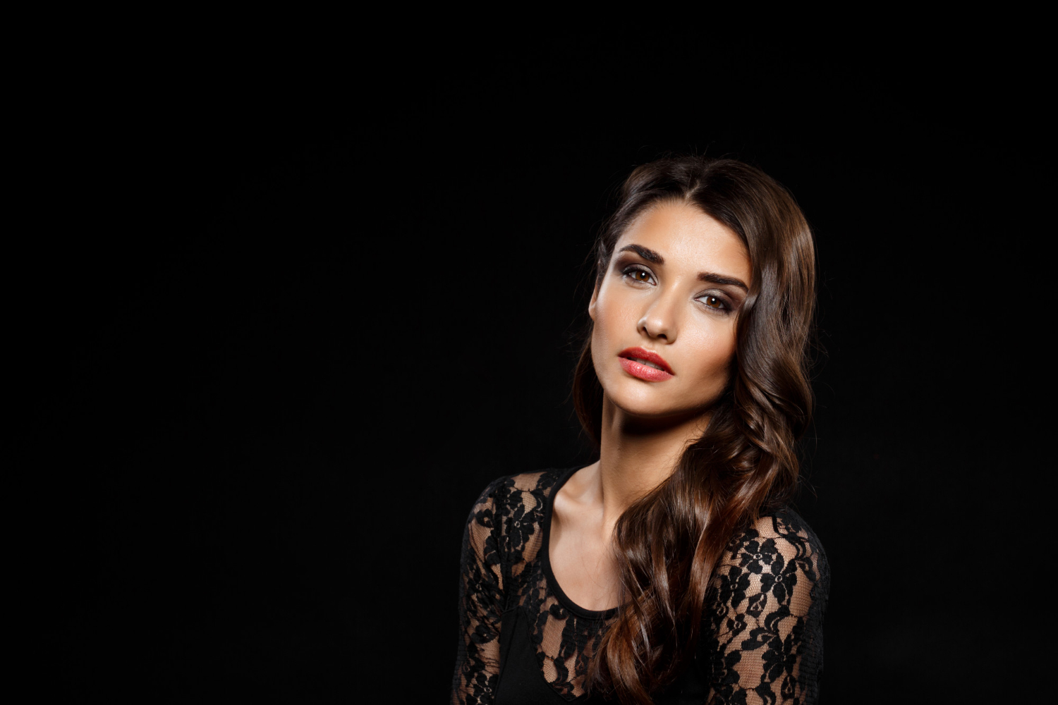 portrait of a beautiful latin woman in a black dress on dark wal