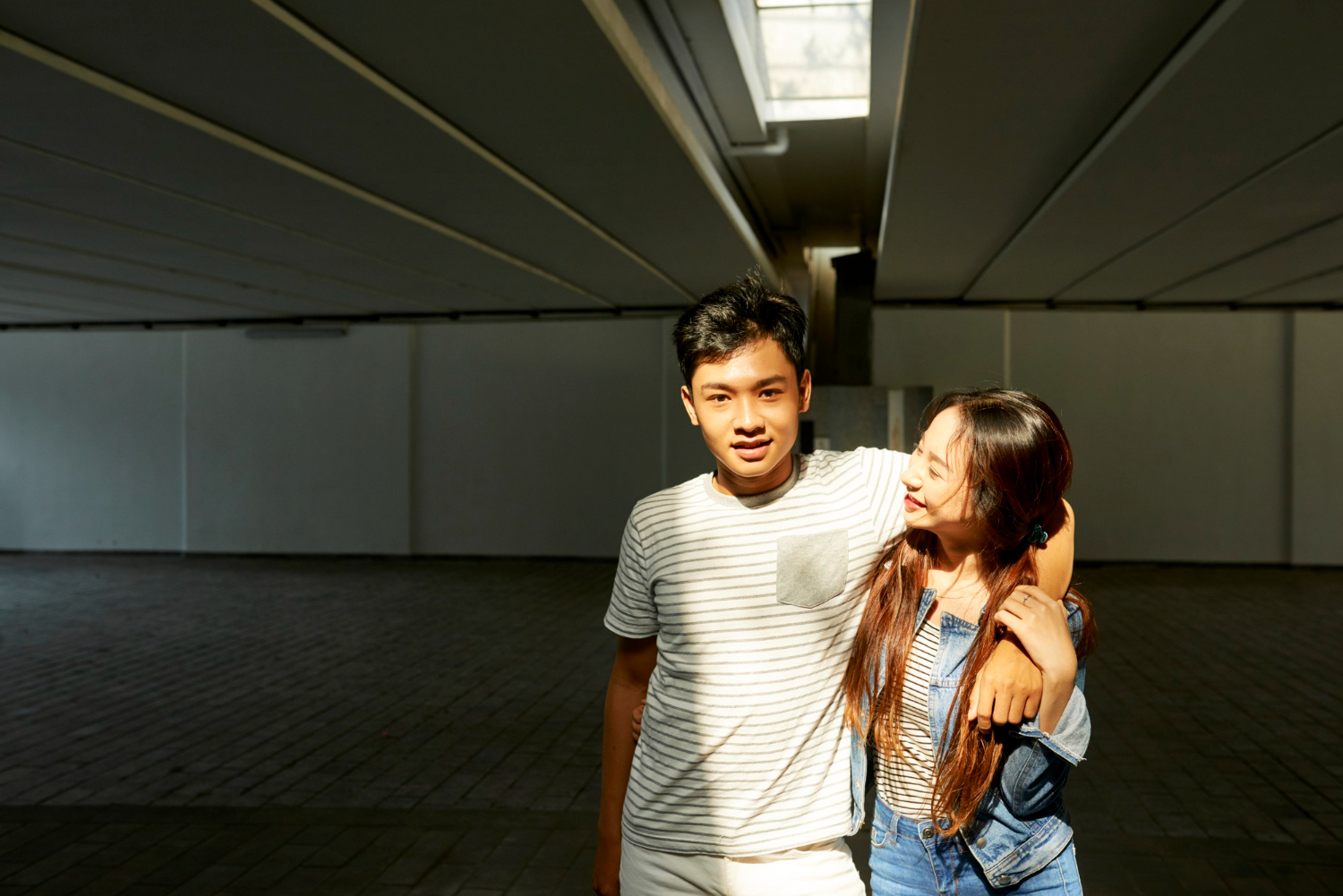 portrait happy young asian chinese couple love hugging when standing sunrays underground