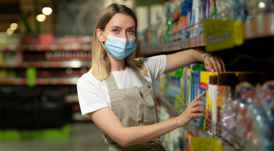 woolworths staff member in protective face mask filling shelves in the supermarket