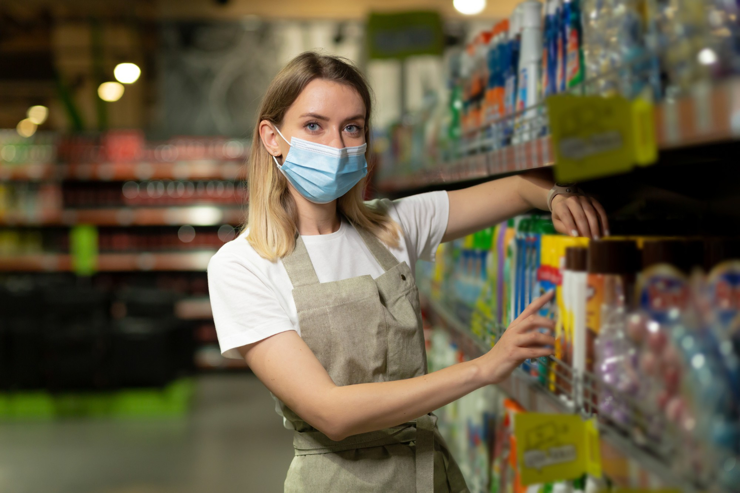 woolworths staff member in protective face mask filling shelves in the supermarket