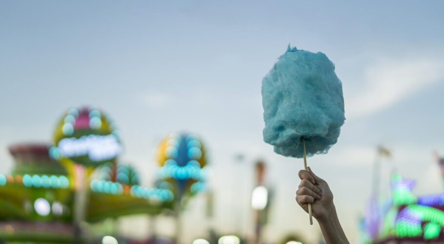 selective focus shot female holding cotton candy amusement park