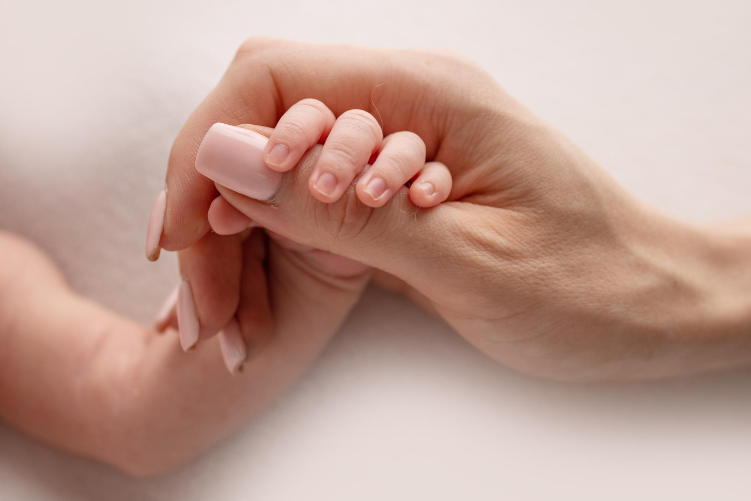 small hand with tiny fingers arm mother newborn baby holding finger parents after birth